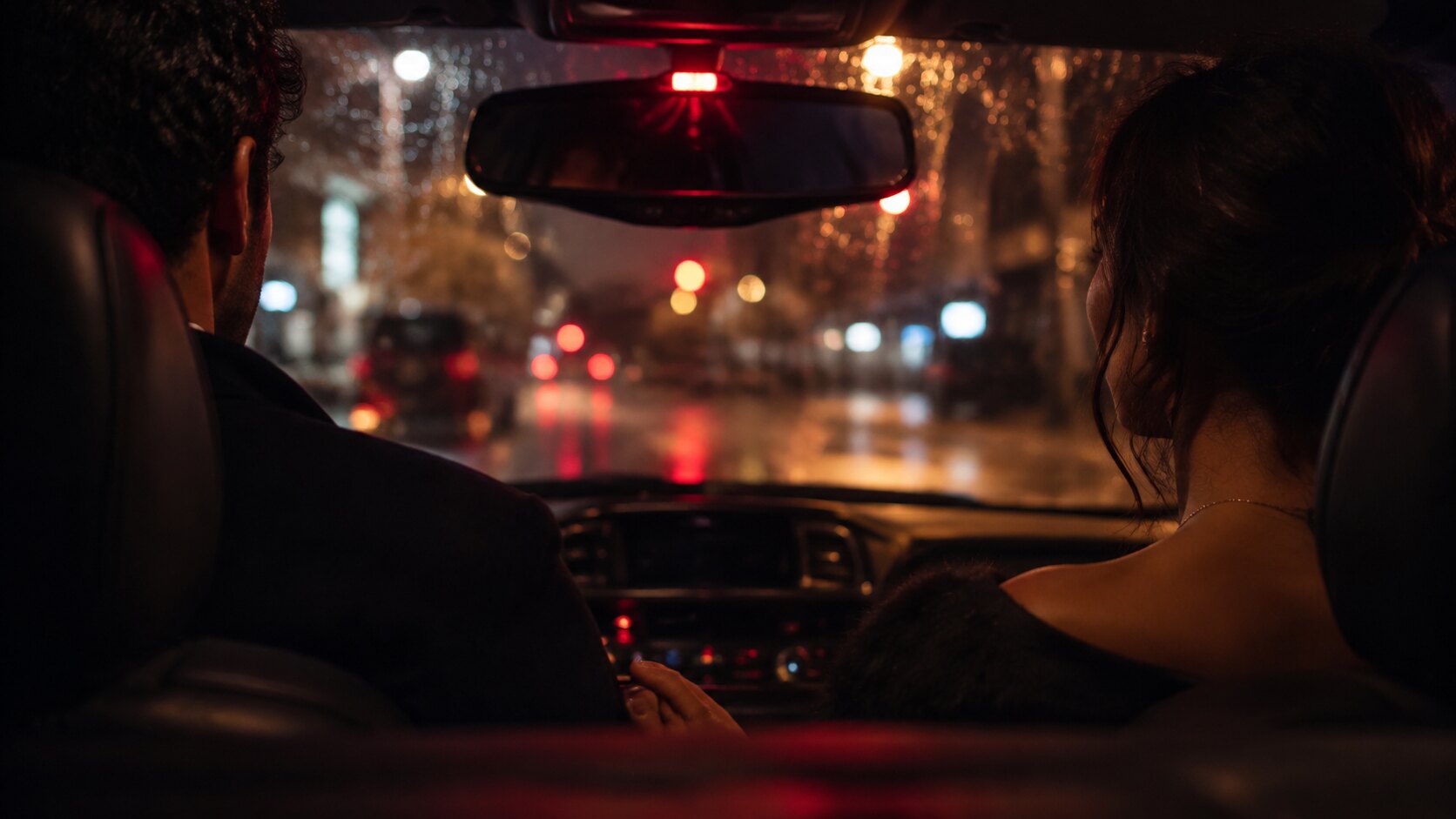 Interior de un taxi de noche bajo la lluvia, con el retrovisor y una luz roja encendida